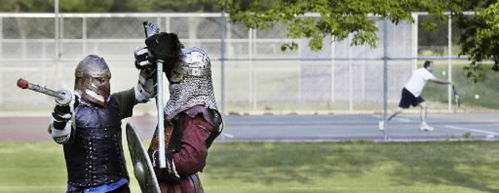 As two medieval combatants battle each other with lances and swords, tennis players battle each other in the background at Elephant Park in north Fargo. Dave Wallis / The Forum